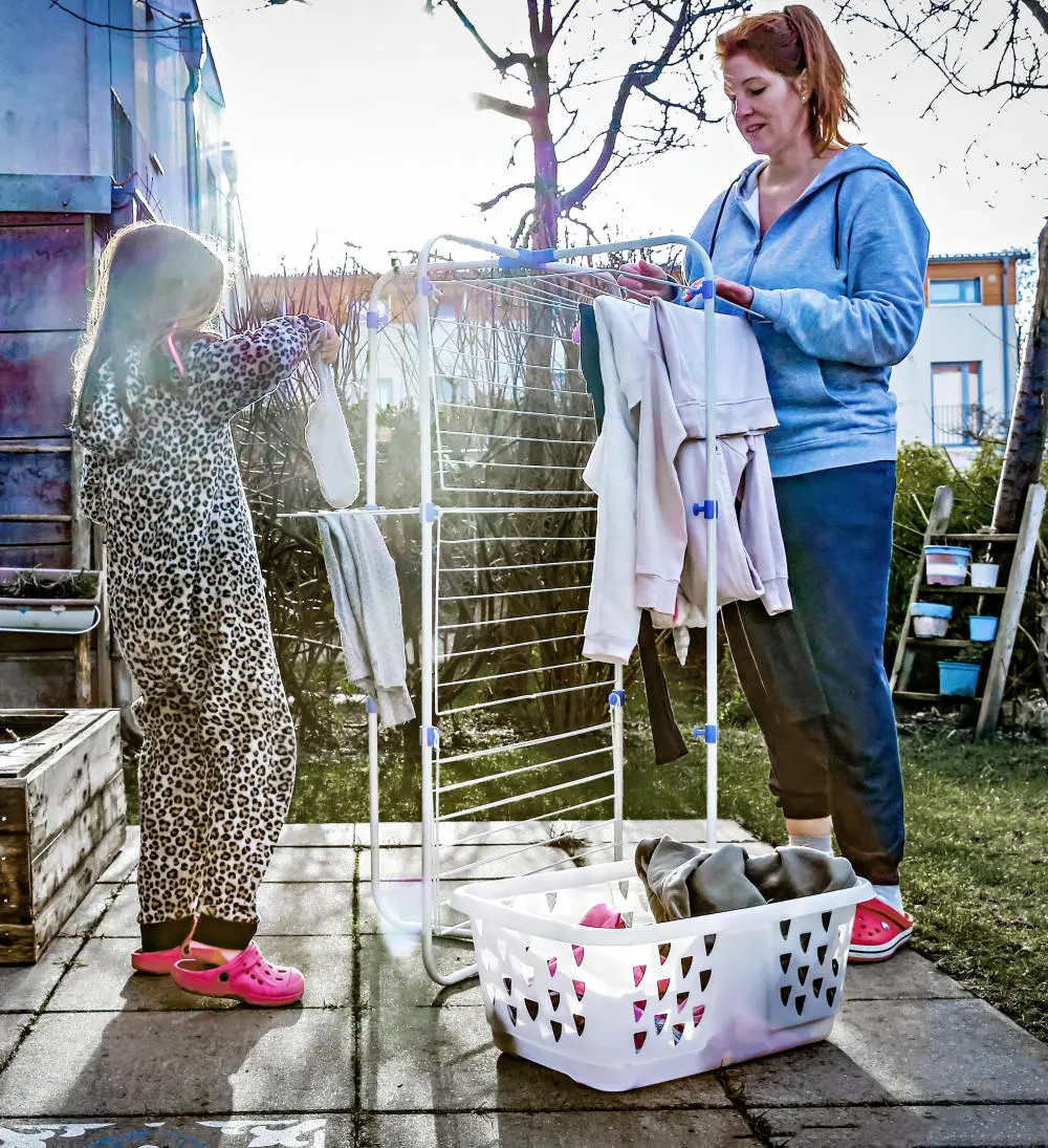 Eine Frau und ein Kind hängen Wäsche im Garten auf