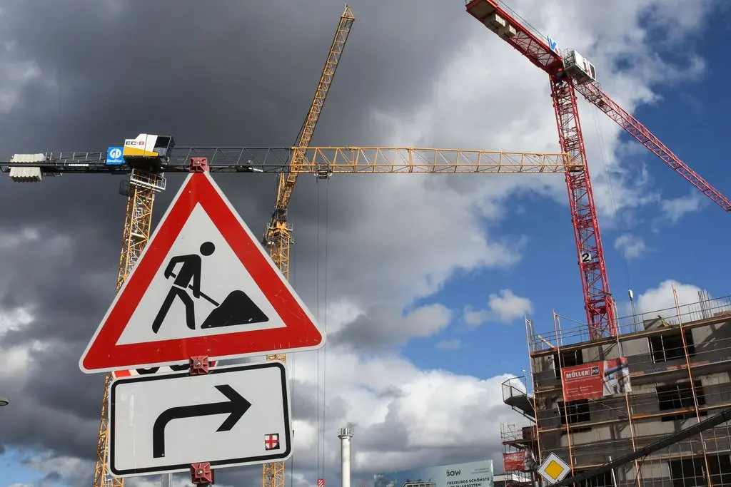 Baubrache in der Krise Baukräne vor einer Baustelle