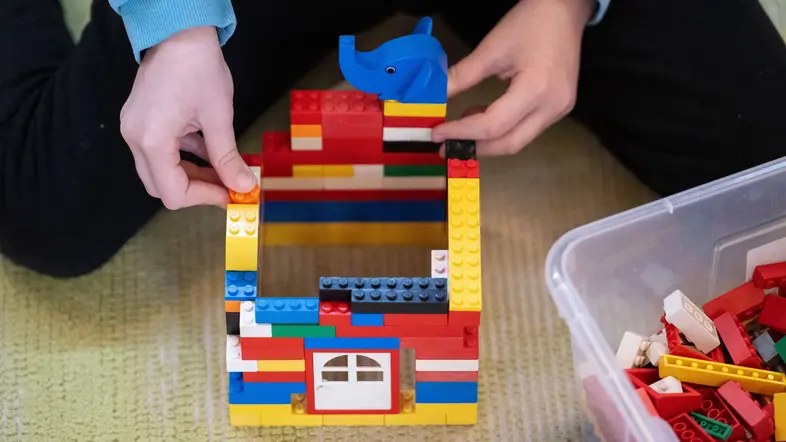 Ein Kind spielt in einem Kindergarten mit Bausteinen.