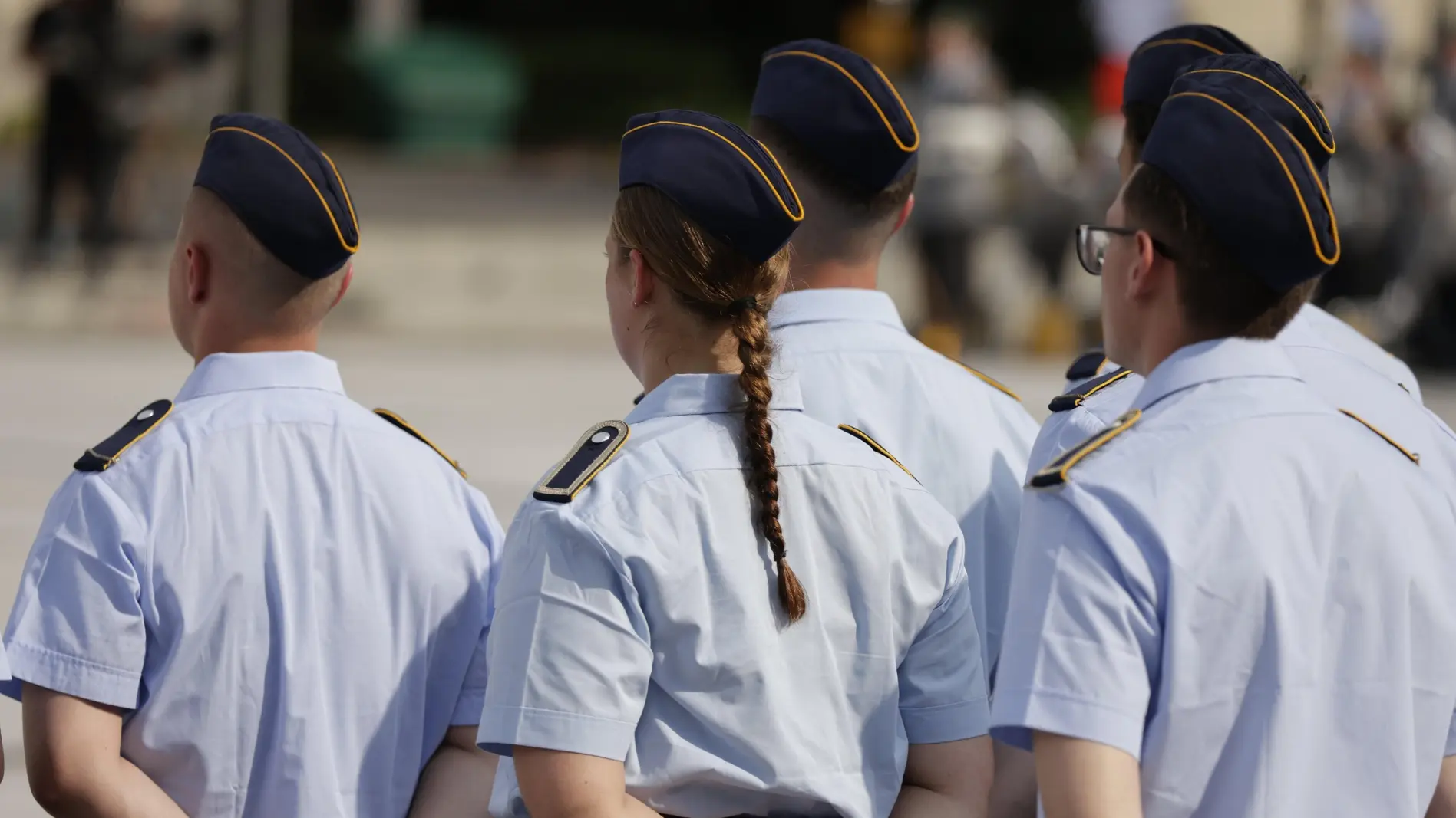 Drei Rekrutinnen und Rekruten von hinten bei ihrem Gelöbnis