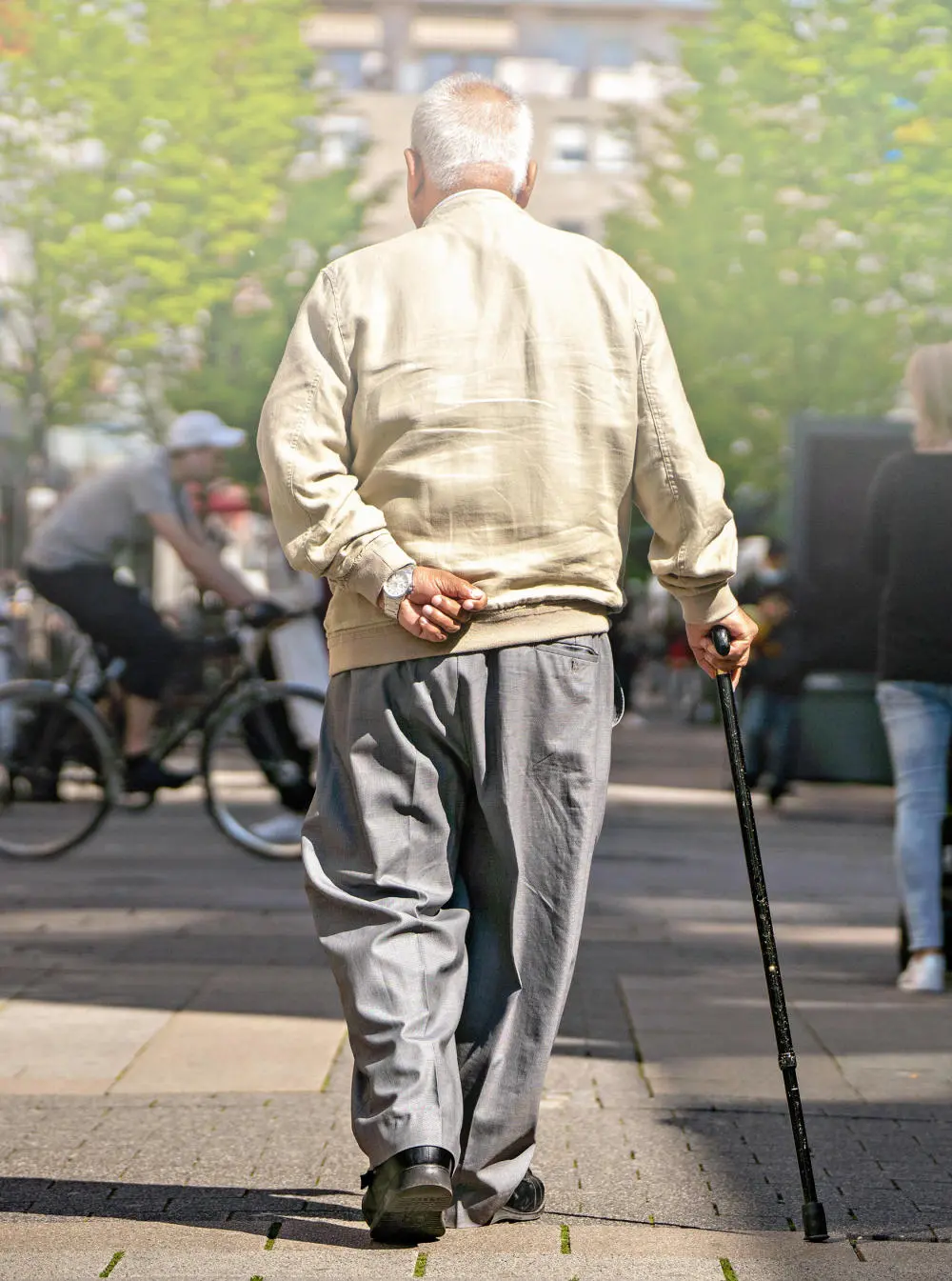 Ein älterer Mann mit Gehstock bei einem Spaziergang.