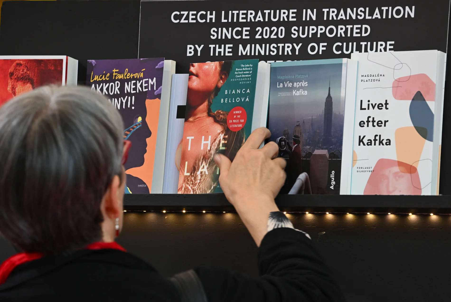 Frau legt ein tschechiches Buch in ein Regal zurück