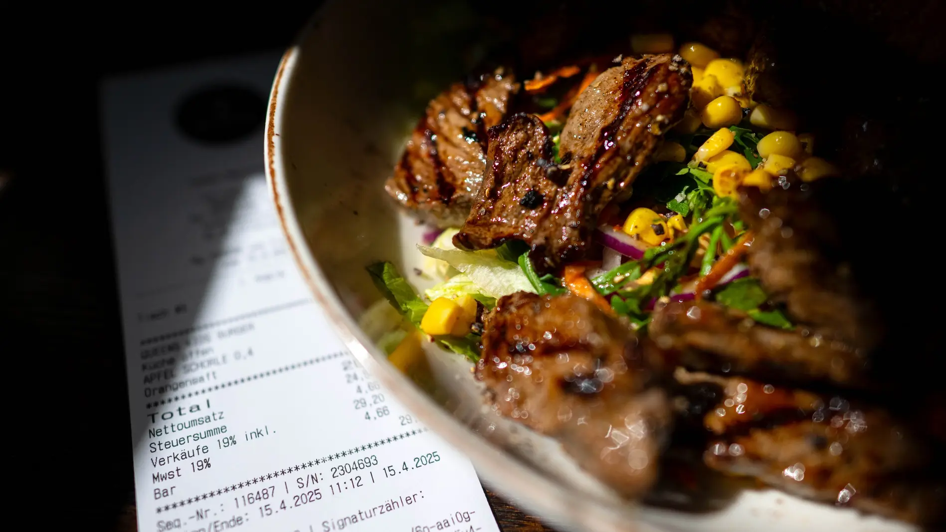 Eine Rechnung der Mehrwertsteuer neben eine vollen Teller in einem Restaurants.