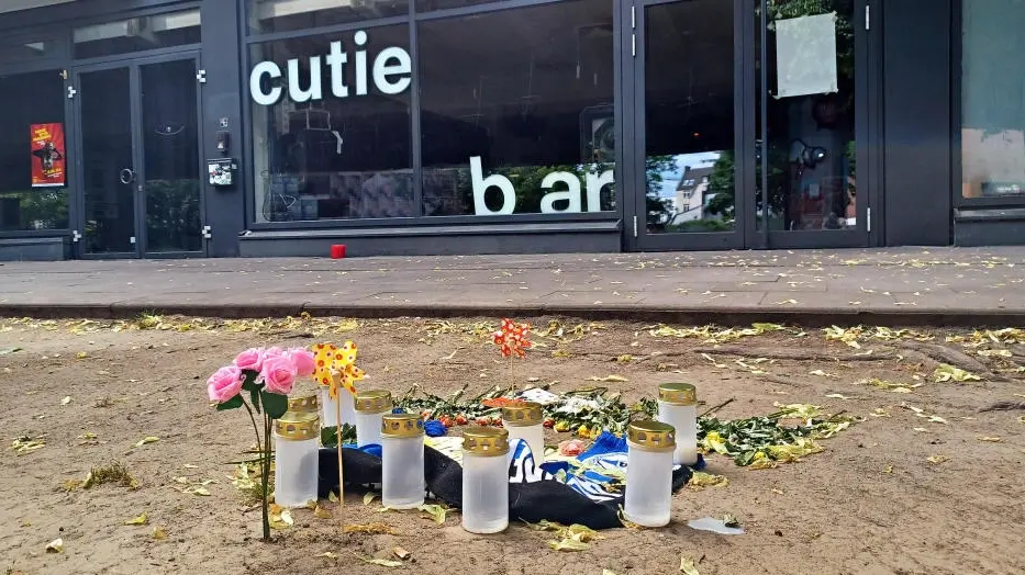 Kerzen und Blumen auf dem Boden vor der Cutie Bar in Bielefeld