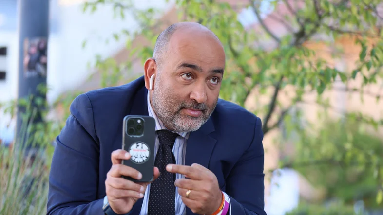 Omid Nouripour zeigt auf das Eintracht-Frankfurt-Logo auf seinem Handy