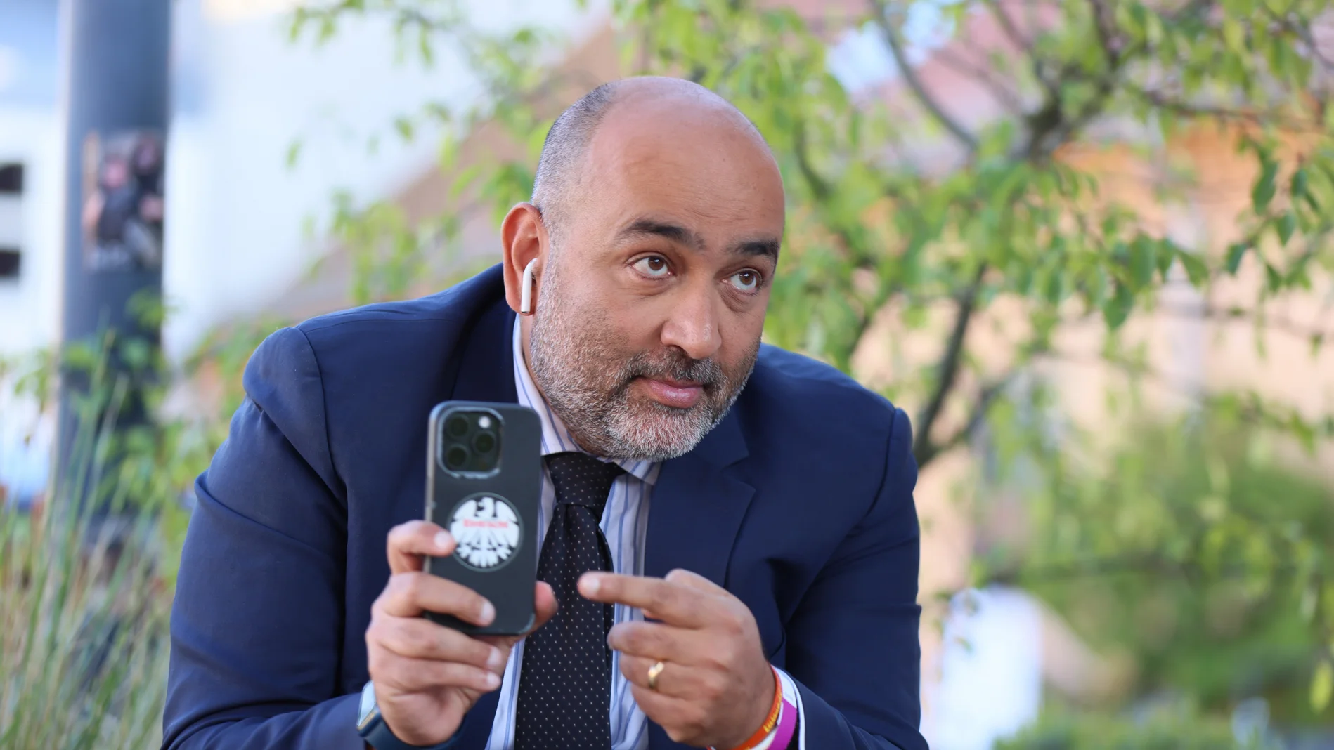 Omid Nouripour zeigt auf das Eintracht-Frankfurt-Logo auf seinem Handy