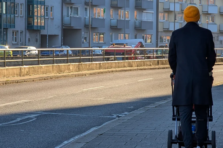 Mann schiebt Kinderwagen auf dem Bürgersteig