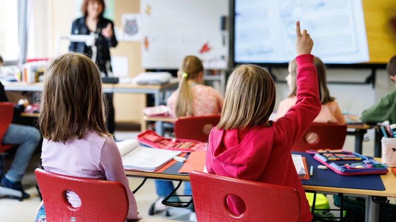 Schüler sitzen während des Unterrichts auf ihren Plätzen und melden sich.