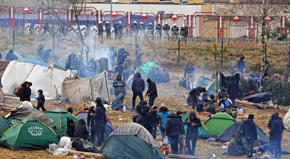 Camp an der Grenze zu Polen Menschen stehen um kleine Zelte herum, es qualmt