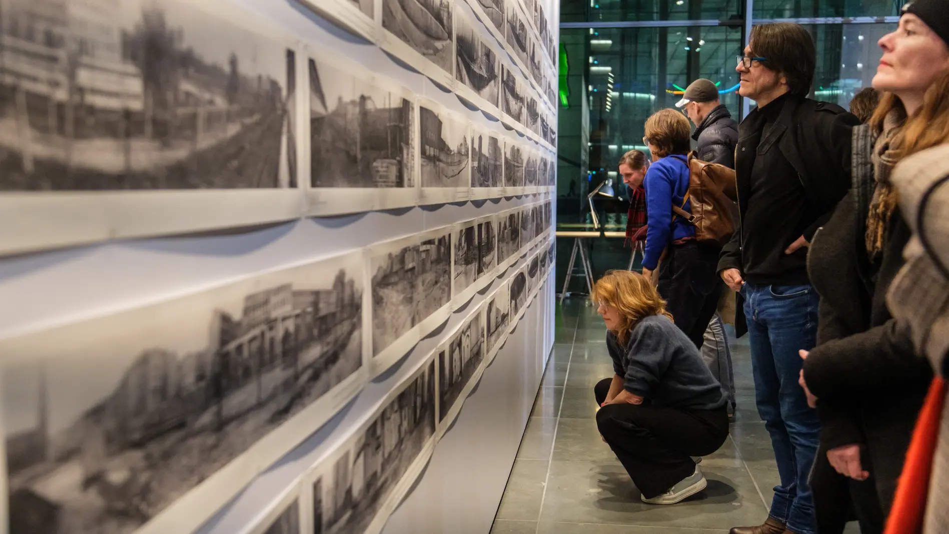 Ausstellung zum Mauerfall-Jubiläum Besucher der Ausstellung blicken auf Bilder der Berliner Mauer