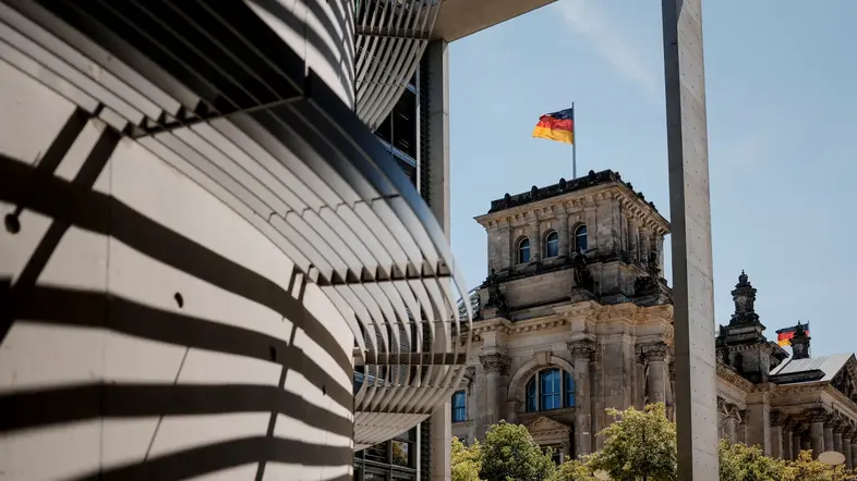 Das Reichstagsgebäude erstreckt sich im Hintergrund vor blauem Himmel