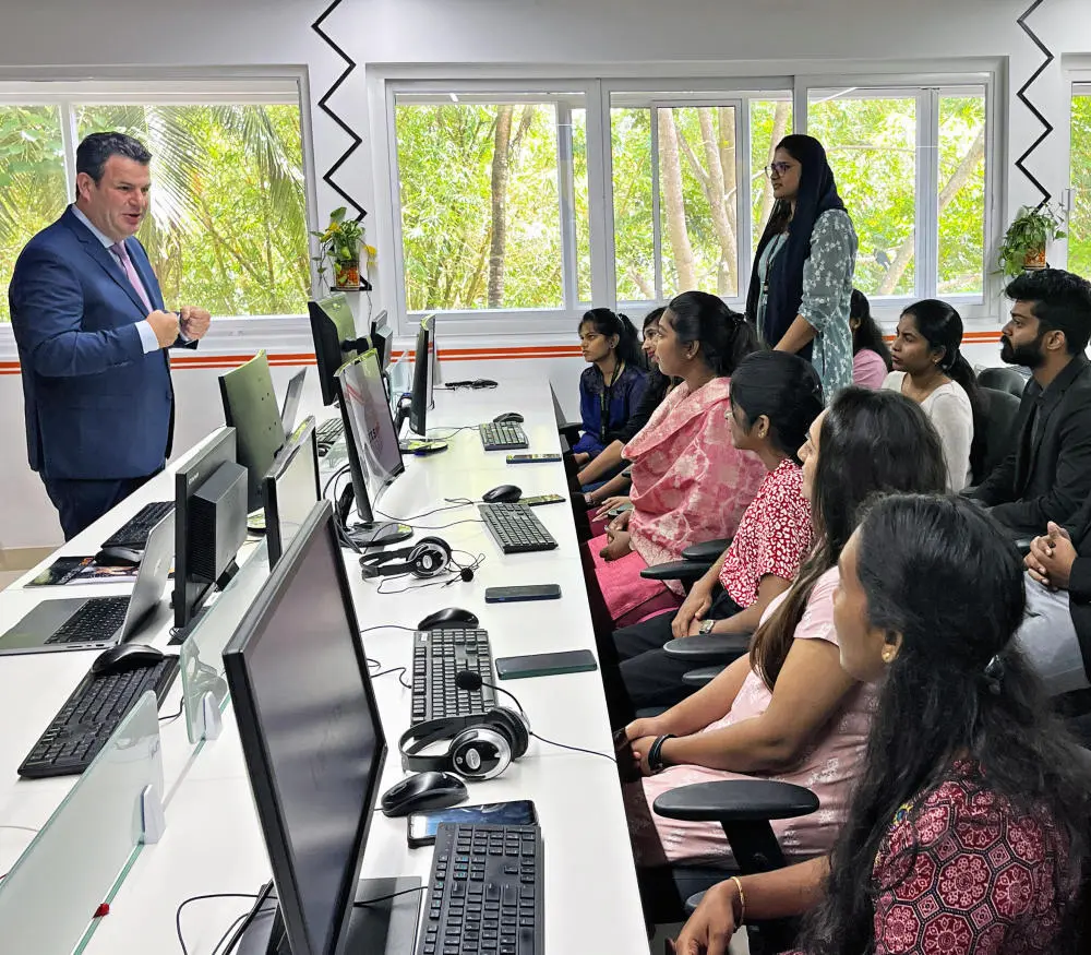 Bundesarbeitsminister Hubertus Heil spricht mit IT-Experten und jungen Menschen aus Indien, in einem Schulungsraum mit Computern.