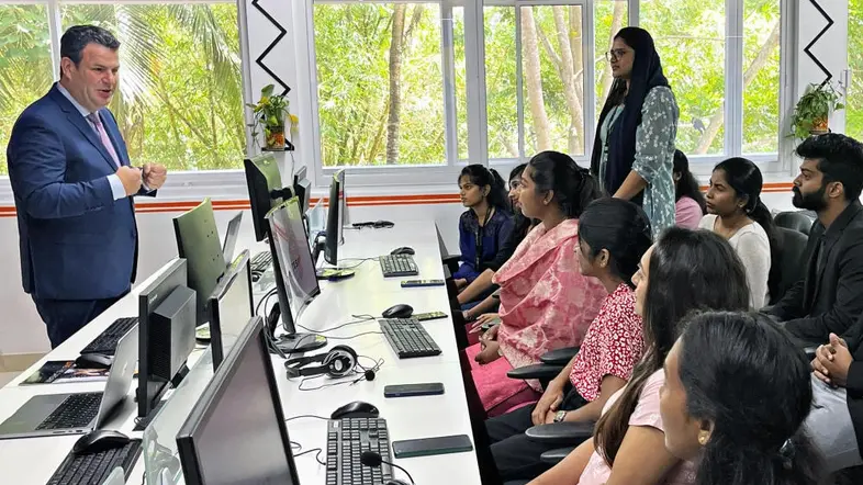 Bundesarbeitsminister Hubertus Heil spricht mit IT-Experten und jungen Menschen aus Indien, in einem Schulungsraum mit Computern.