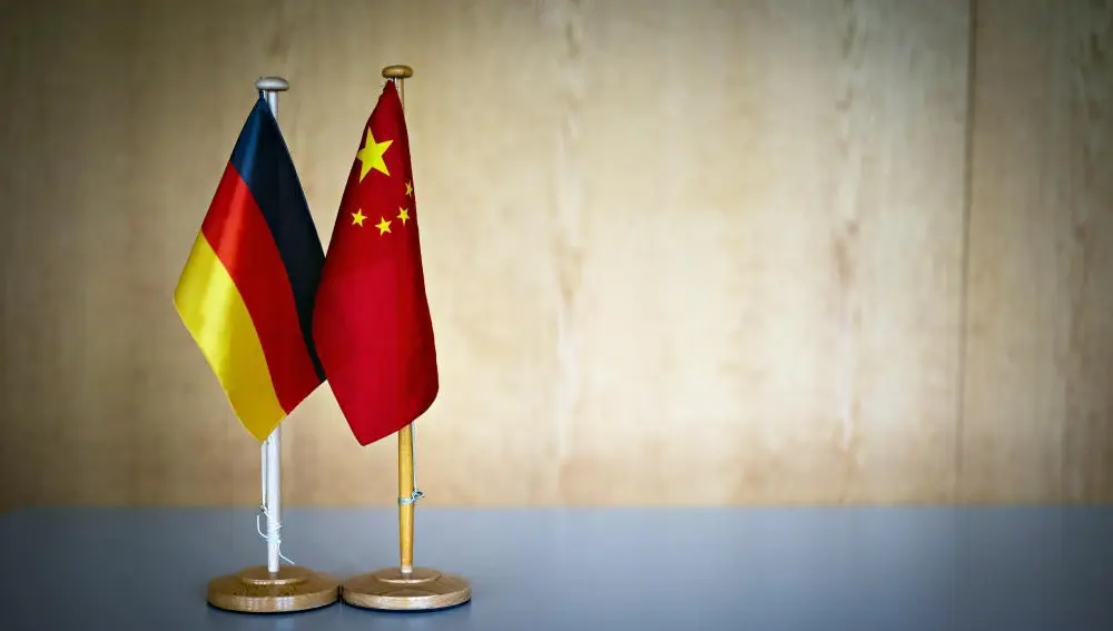 Das Bild zeigt eine deutsche Flagge neben einer chinesischen Flagge auf einem Tisch.