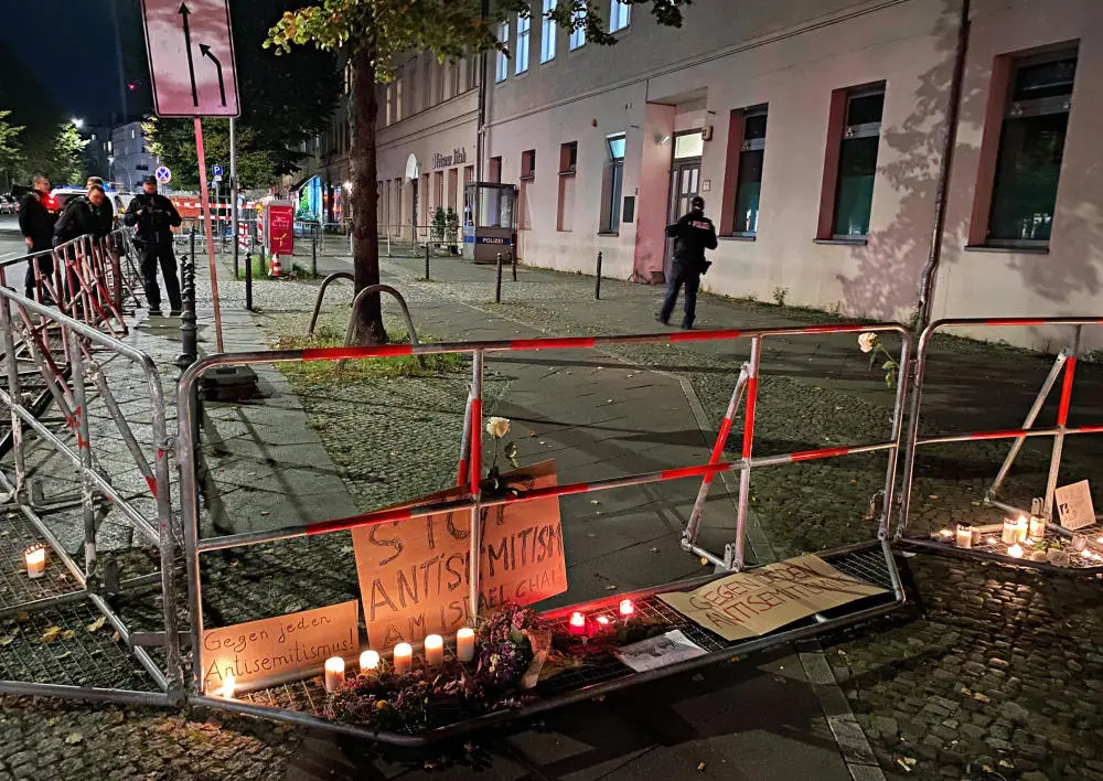 Brennende Kerzen stehen an Schildern mit der Aufschrift "Stop Antisemitism" an dem abgesperrten Bürgersteig vor dem jüdischen Gemeindezentrum an der Berliner Brunnenstraße.