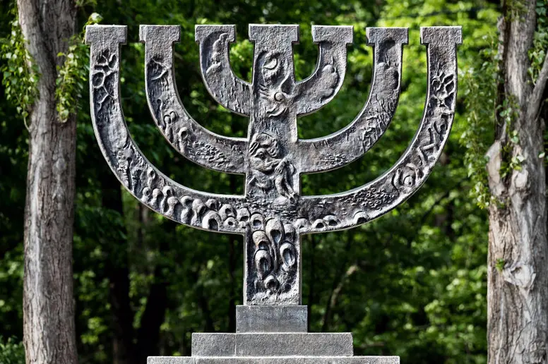 Ein Menorah Denkmal, im Hintergrund grüne Bäume