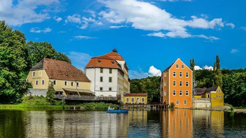 Gebäude der "Obermühle", spiegeln sich im Wasser.