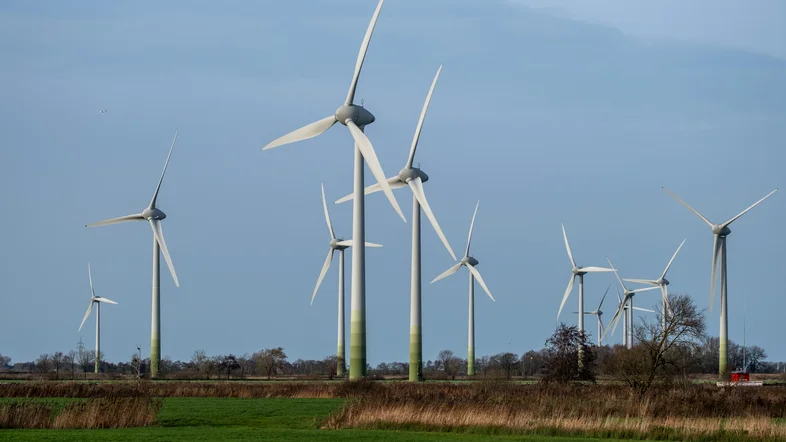 Mehrere Windräder vor einem blauen Himmel
