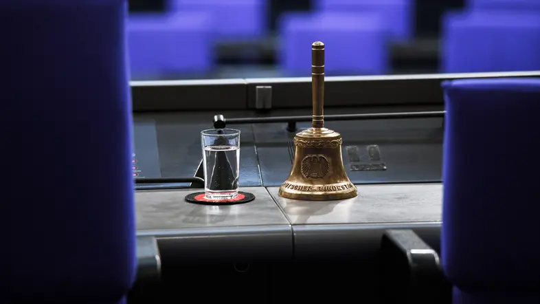 Stuhl der Bundestagspräsidentin mit einem Glass Wasser und der Glocke im Fokus
