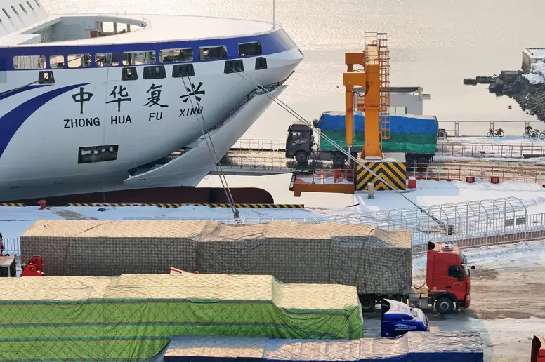 Ein großes Schiff steht an einem Hafen vor Containern