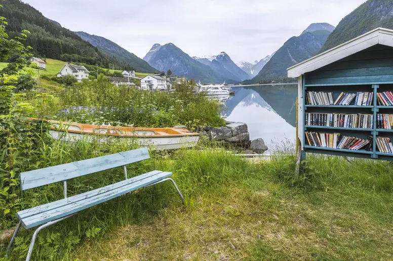 Öffentliches Bücherregal und Bank im Freien am Fjord in Norwegen.