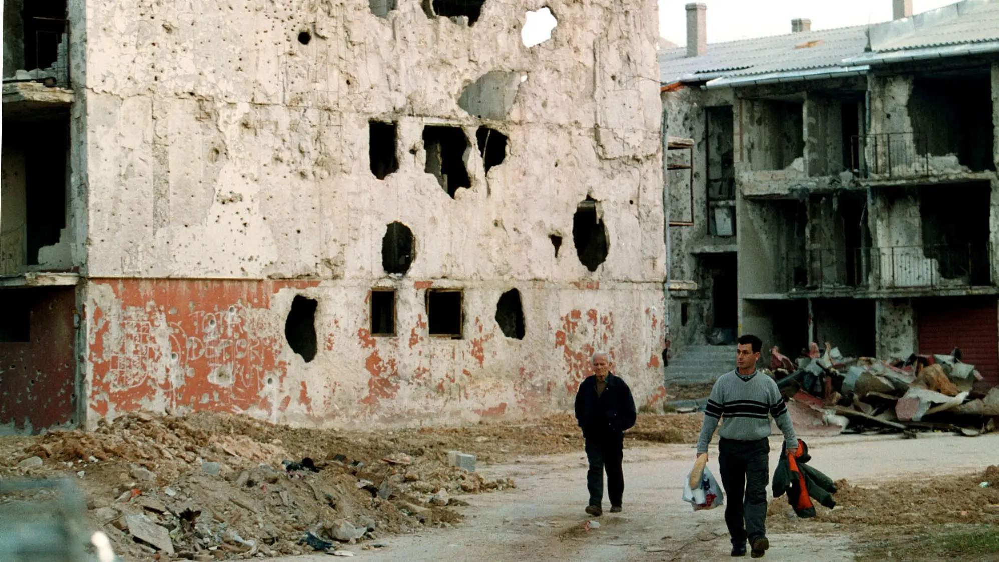 Jahrestag des Kriegsbeginns in Bosnien und Herzegowina Zwei Männer gehen an von Kugeln und Granaten durchlöcherten Gebäuden an der ehemaligen Frontlinie in Sarajewo vorbei.