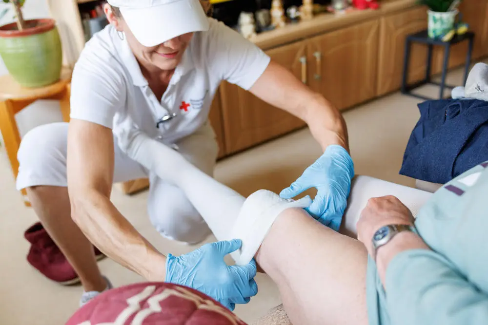 Pflegefachkraft zieht einer Bewohnerin Kompressionsstrümpfe an
