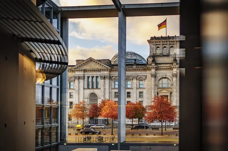 Das Reichstagsgebäude spiegelt sich in einer Scheibe des Paul-Löbe-Haus am frühen Morgen. 