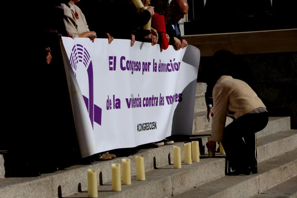 Frauen legen Kerzen vor einem Plakat nieder