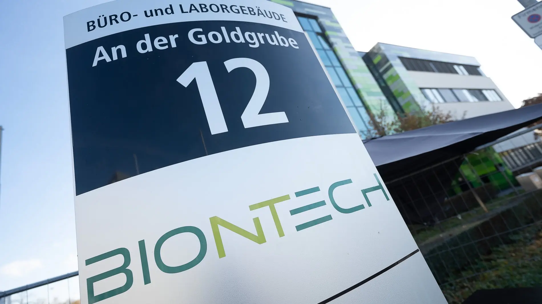 Das BioNTech-Logo steht auf einem Schild mit der Adresse des Firmensitzes.