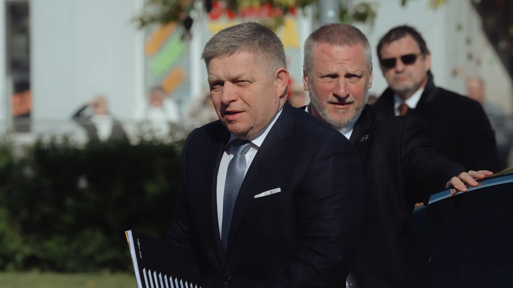 Robert Fico mit einer Akte vor einem Auto