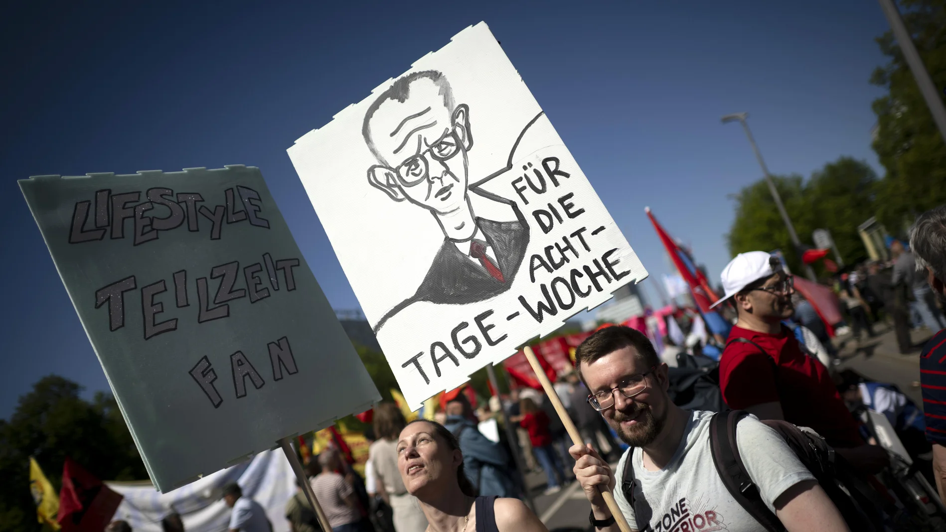 Demonstranten mit einem ironischen Schild "Für die Acht-Tage-Woche"