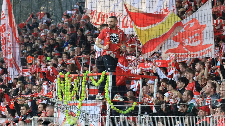 Vorsänger eines Fußballvereins auf einem Podest mit angeketteten Tennisbällen