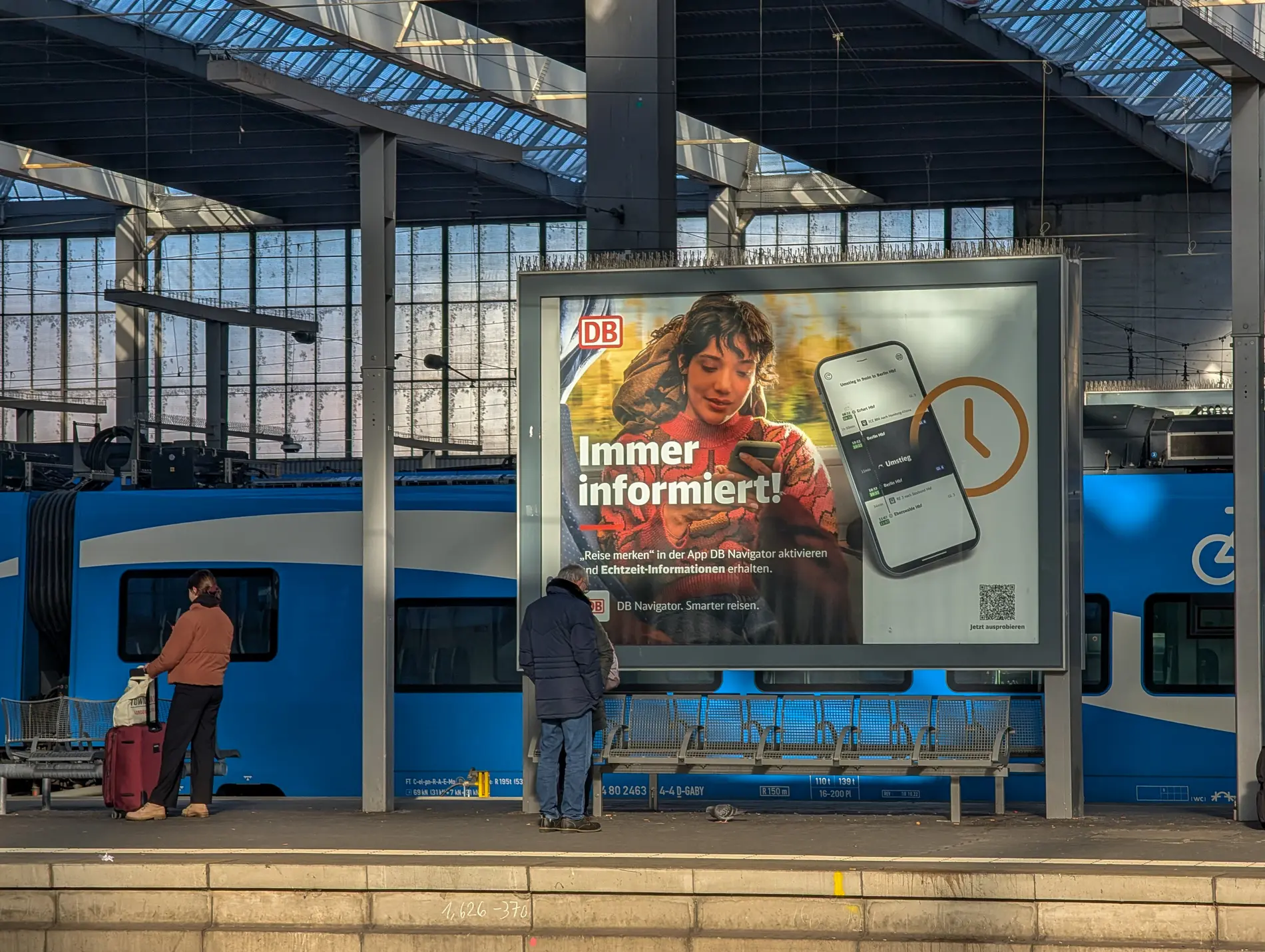 Eine digitale Werbeanzeige der DB auf einem Bahnsteig.