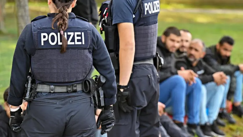 Polizisten bewachen illegale Migranten nach einem Aufgriff bei der Grenze.