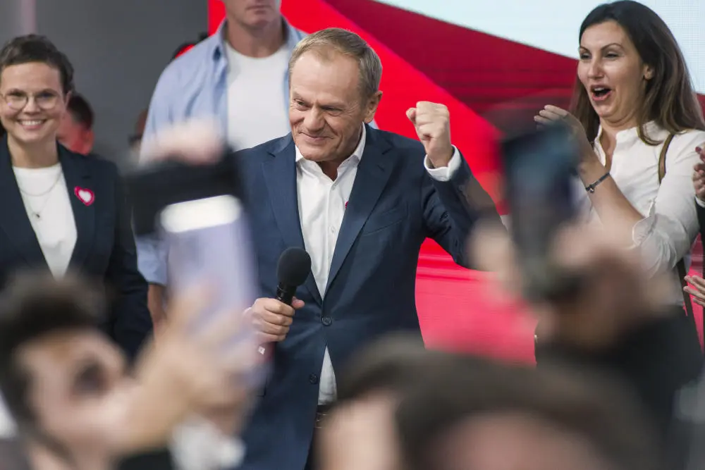 Donald Tusk jubelnd mit einem Mikrofon in der Hand.