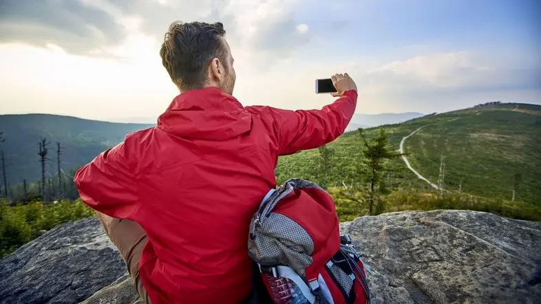 Ein Mann auf einem Felsen nimmt ein Foto auf