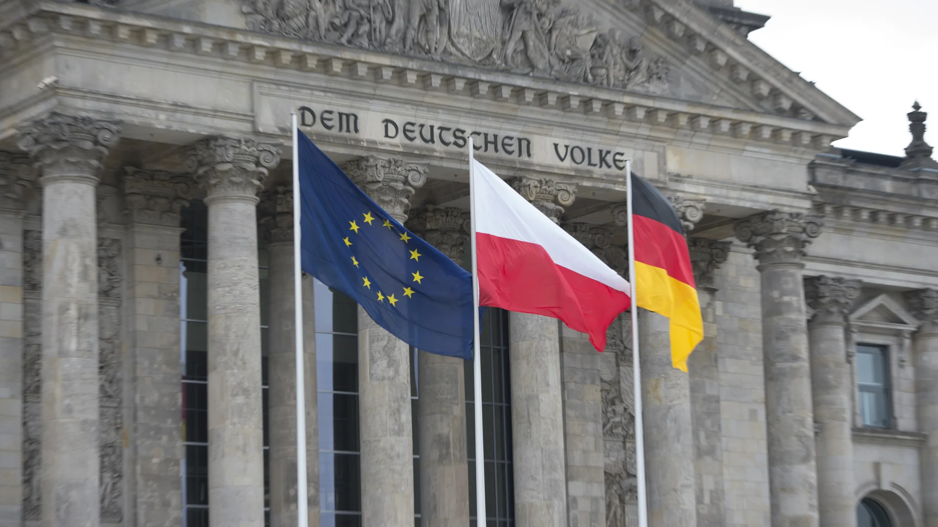  Die europäische, polnische und deutsche Flagge vor dem Reichstagsgebäude