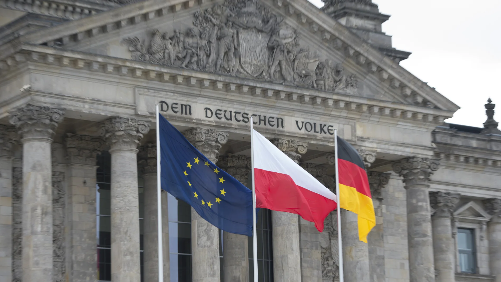  Die europäische, polnische und deutsche Flagge vor dem Reichstagsgebäude