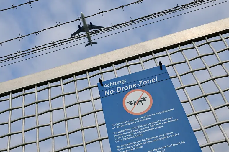 Ein Schild am Zaun eines Flughafens weist auf das Verbot von Drohnenflügen hin