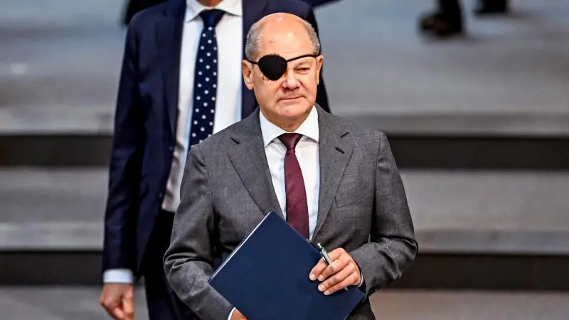 Olaf Scholz im Anzug mit einer schwarzen Augenklappe auf seinem rechten Auge