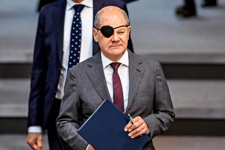 Olaf Scholz im Anzug mit einer schwarzen Augenklappe auf seinem rechten Auge