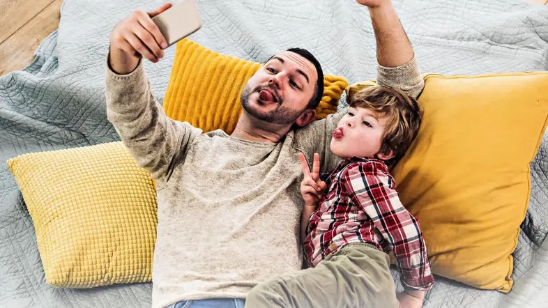 Vater und Sohn schneiden Grimassen vor einer Handykamera