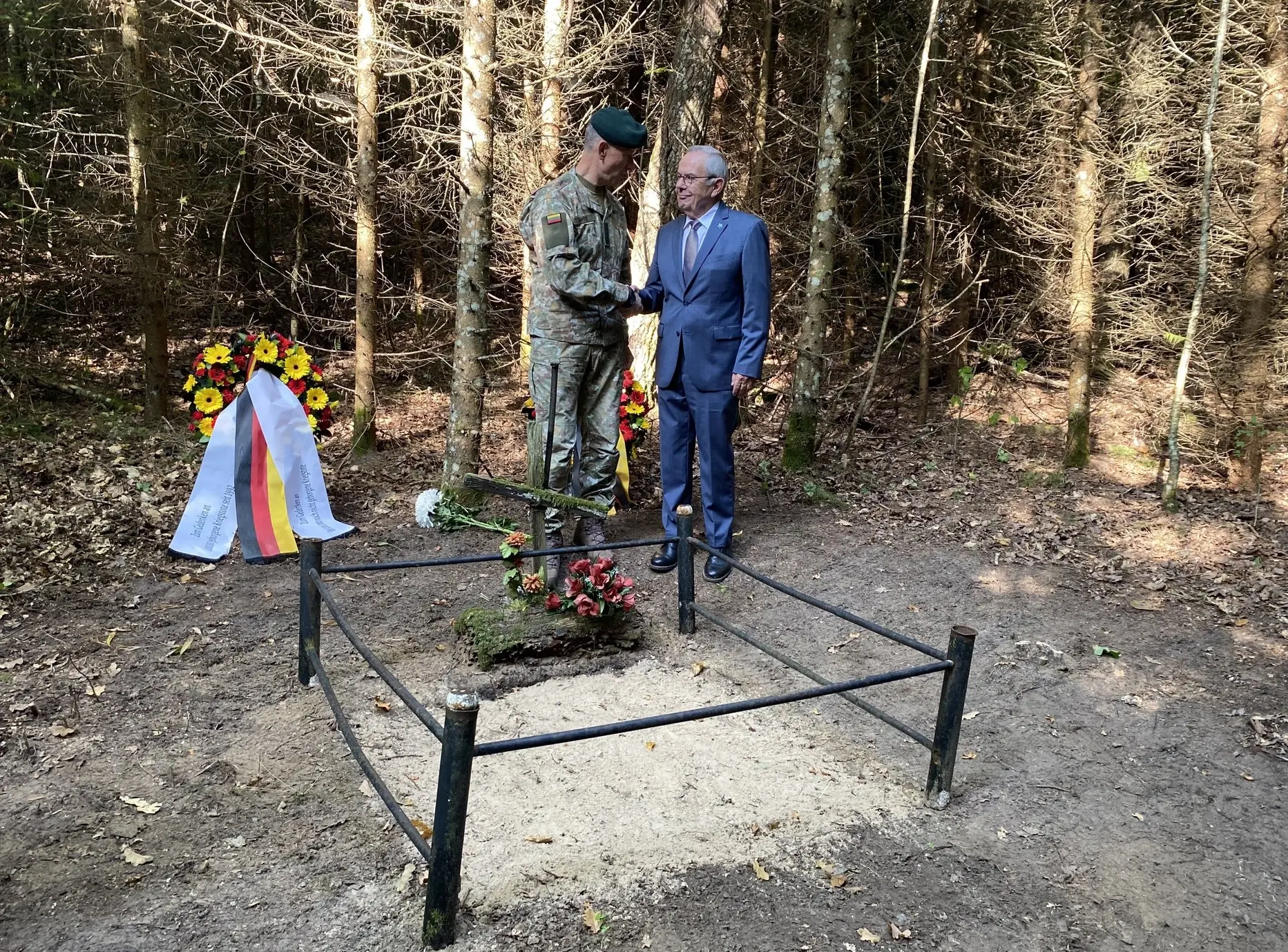Wolfgang Schneiderhan schüttelt Litauens Armeechef an einem Grab die Hand.