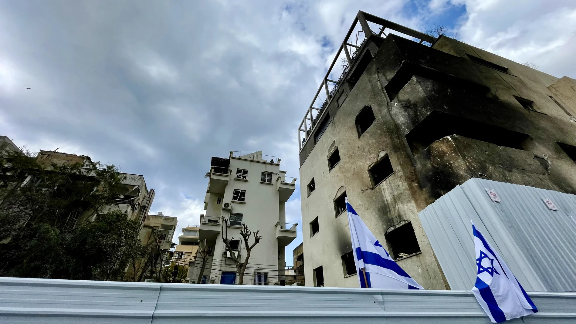 Ausgebranntes Gebäude in Tel Aviv, davor israelische Flaggen
