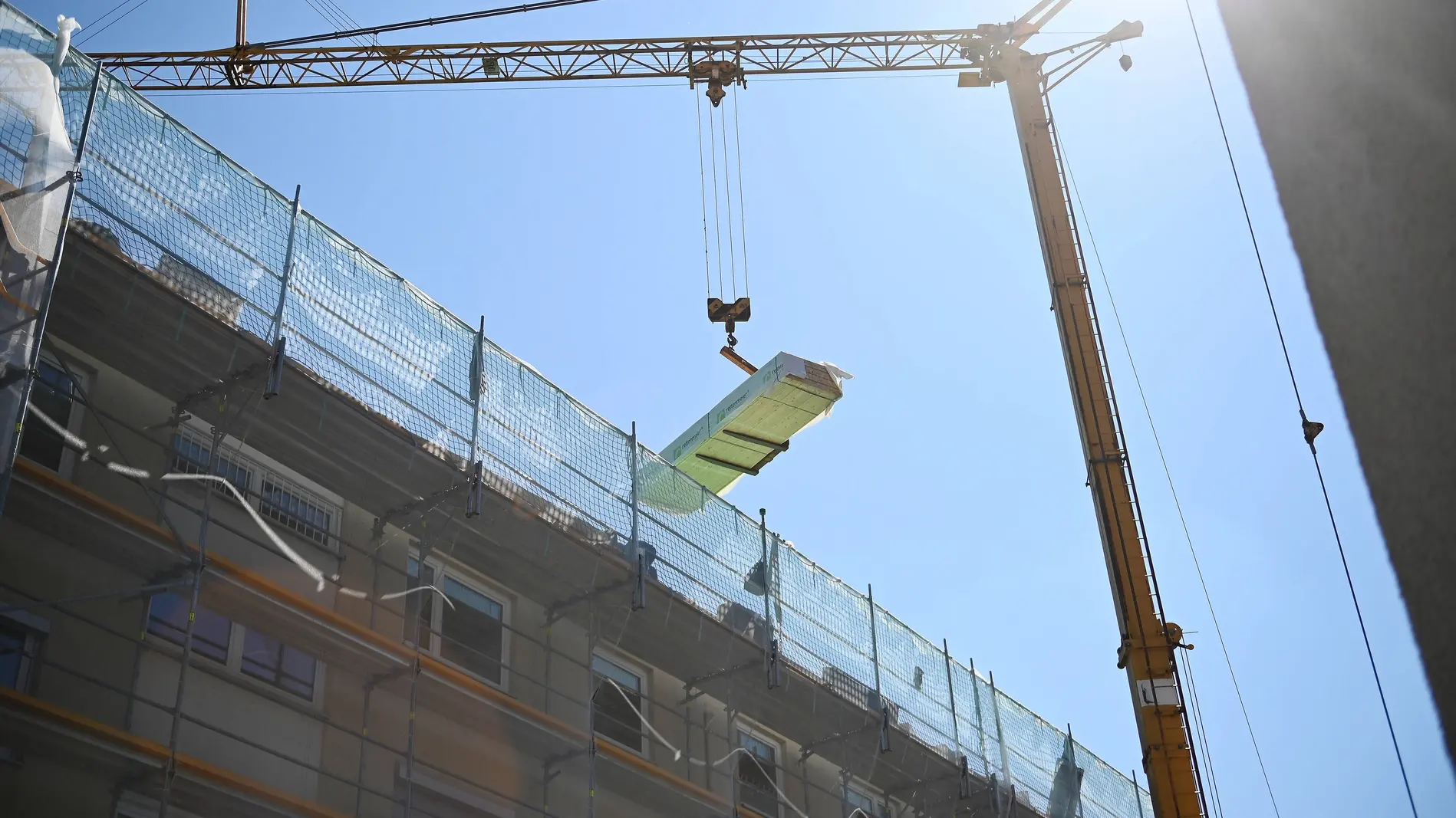 Am Kran hängen Baumaterialen für ein hohes Wohnhaus Am Kran hängen Baumaterialen für ein hohes Wohnhaus
