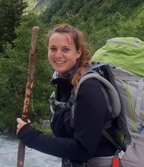 Natascha Schneehain lächelnd beim Wandern mit großem Rucksack