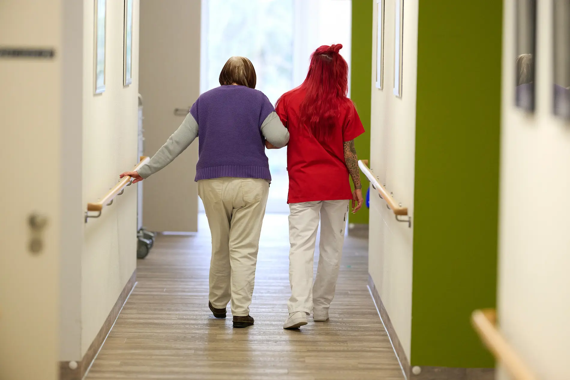 Eine Pflegekraft begleitet im DRK-Pflegezentrum Solferino eine Seniorin durch den Flur.