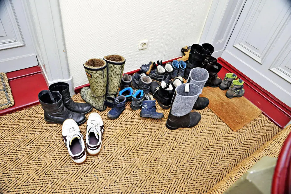Viele Schuhe stehen vor einer Wohnungstür im Hausflur.