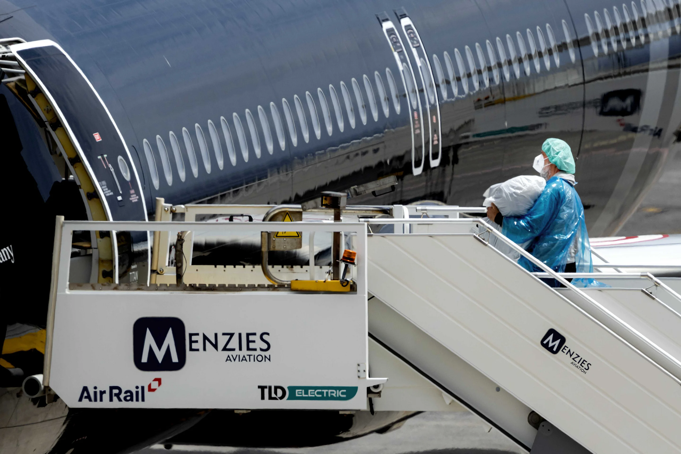 Evakuierte in blauen Schutzanzügen am Flughafen Teneriffa auf einer Treppe